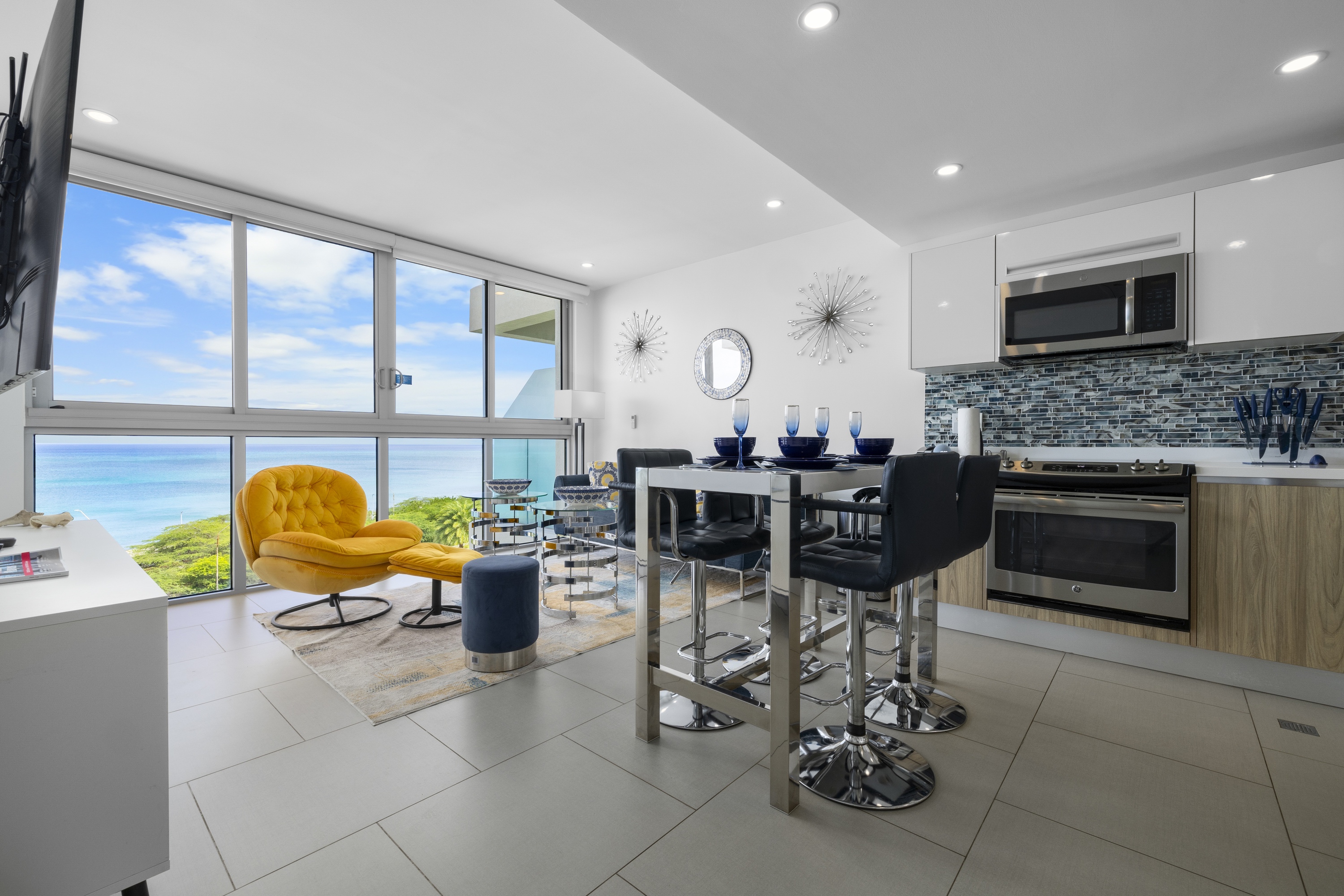 Azure living, kitchen and dining area with floor-to-ceiling ocean views