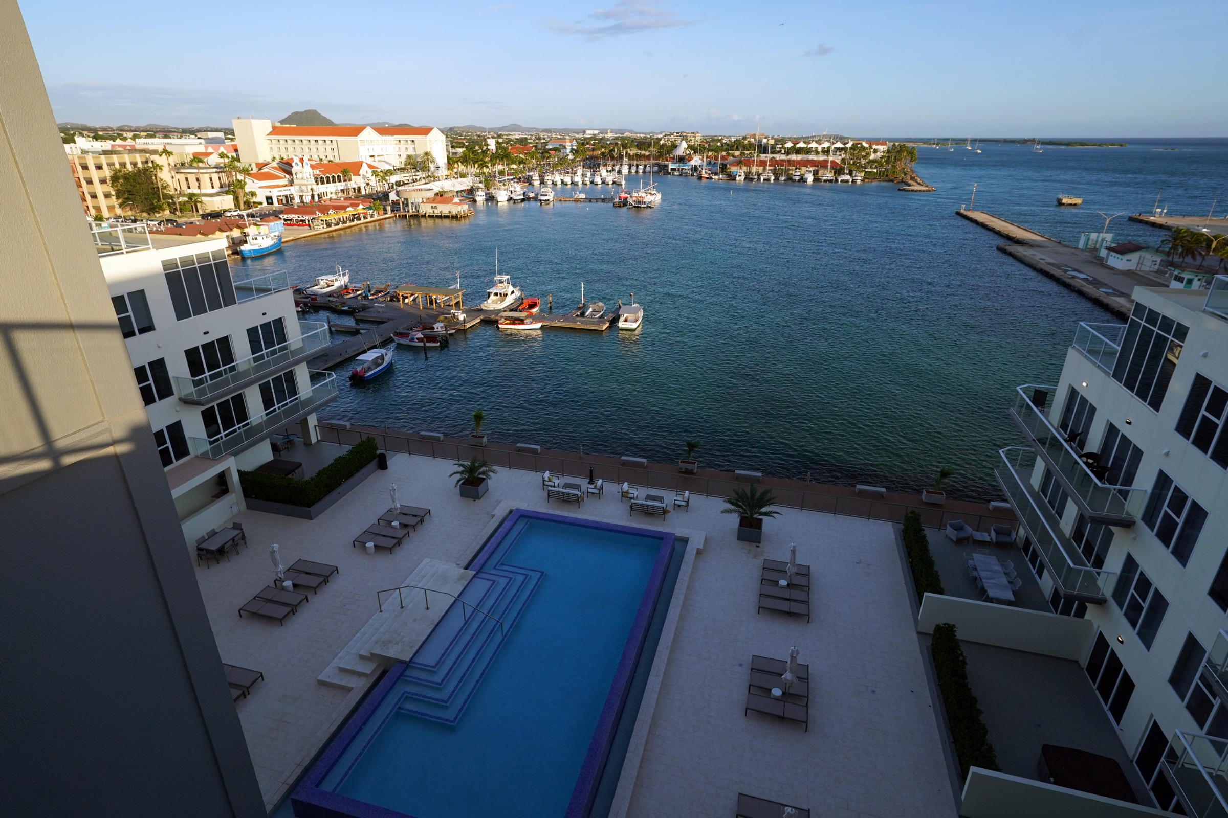 Balcony view over the pool deck, marina, boats and town