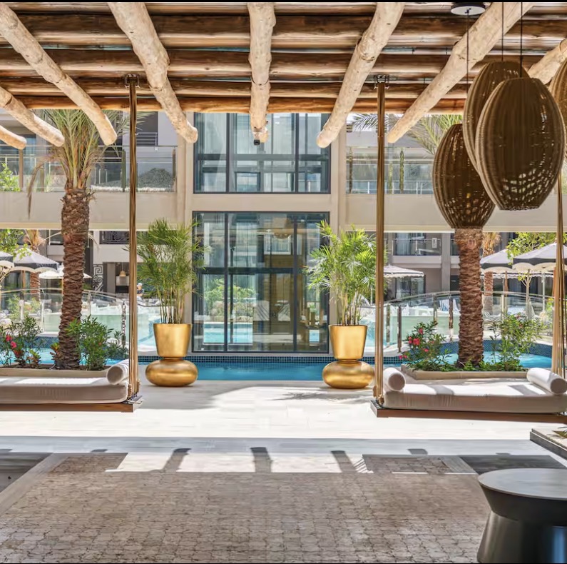 Driftwood pergola with hanging swing beds at Walishali, pool beyond