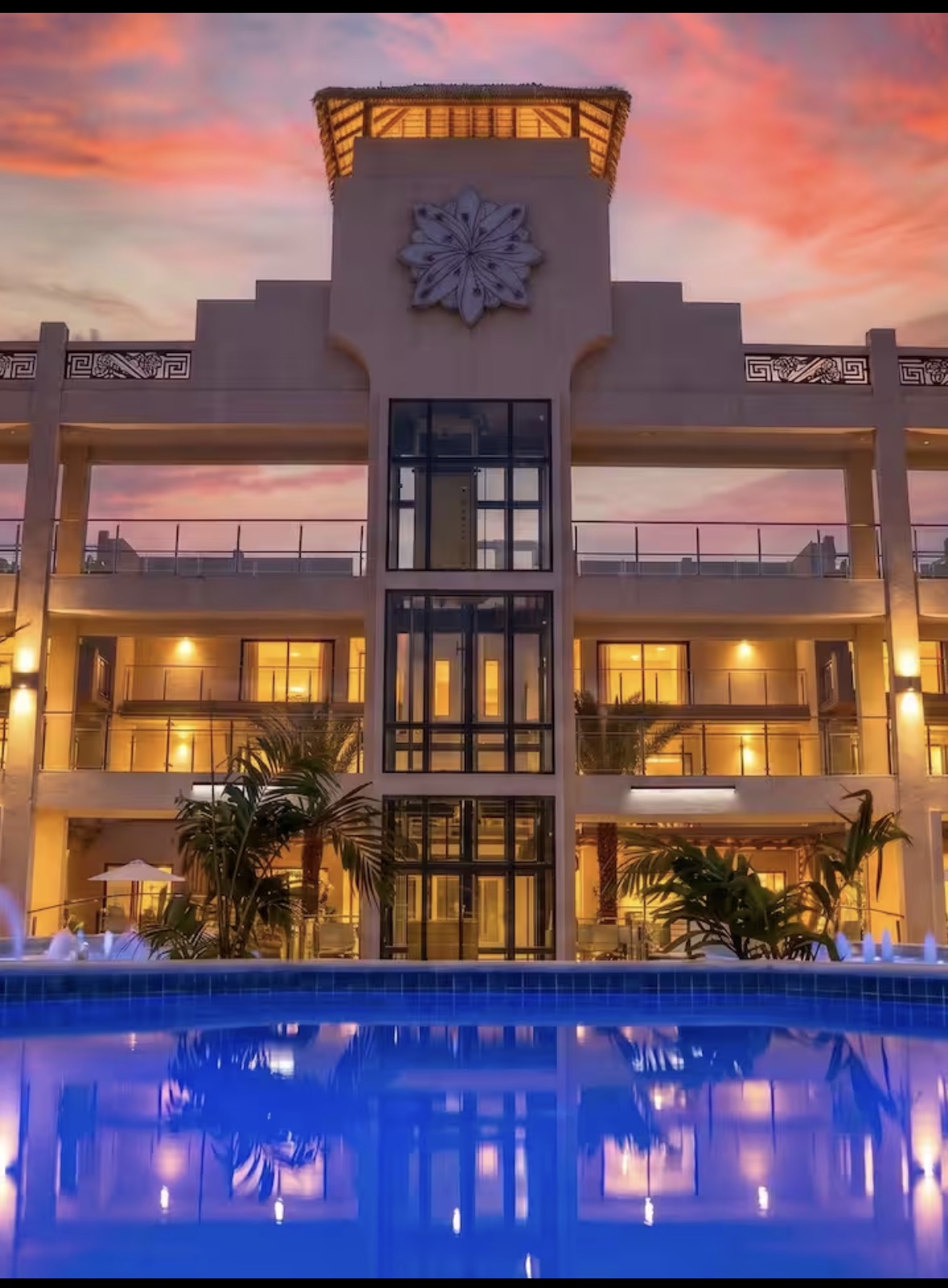 Walishali at dusk: the stone tower and pergola reflected in the fountain pool, pink sky
